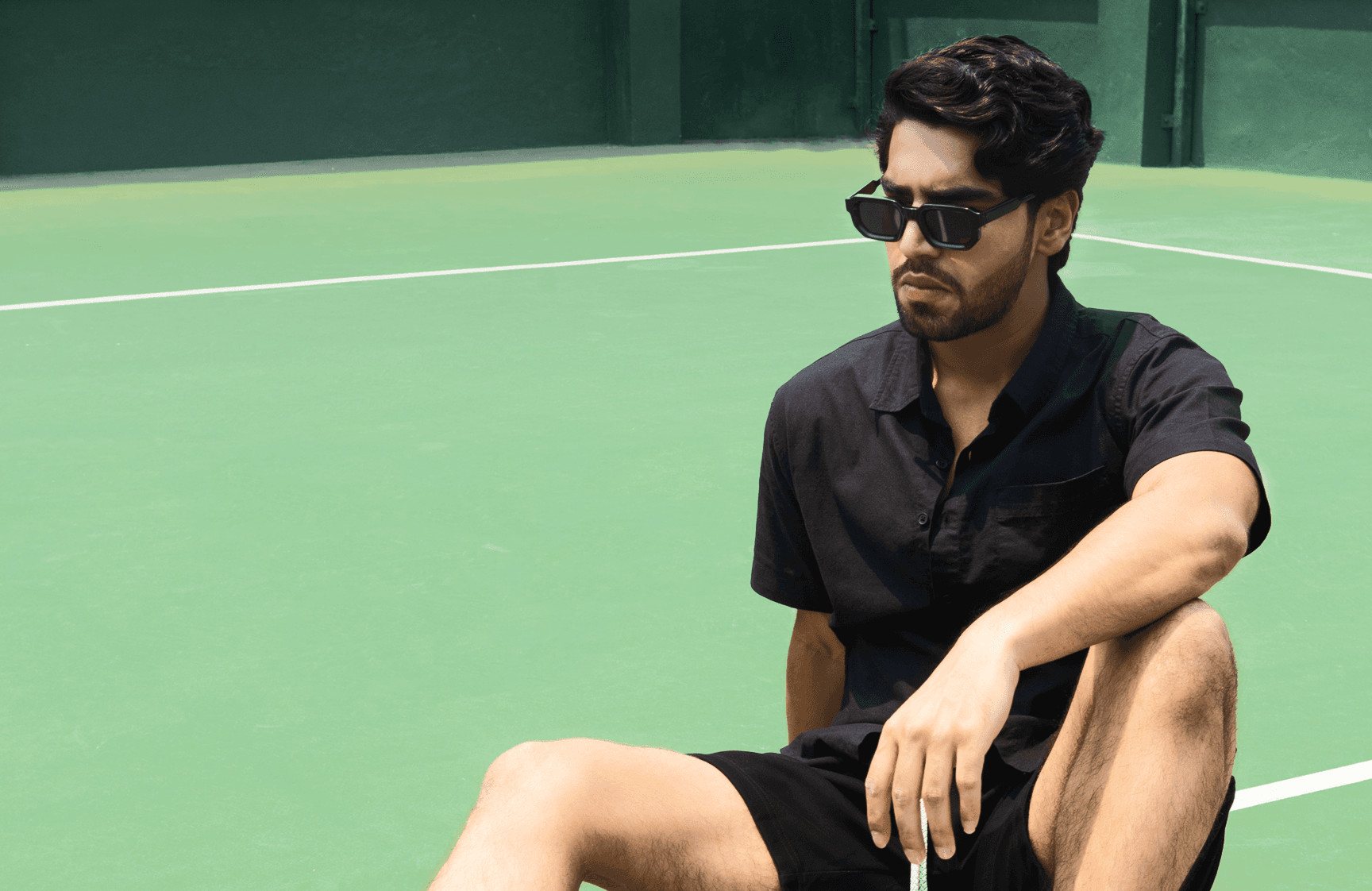 Model in a black linen shirt on a green court
